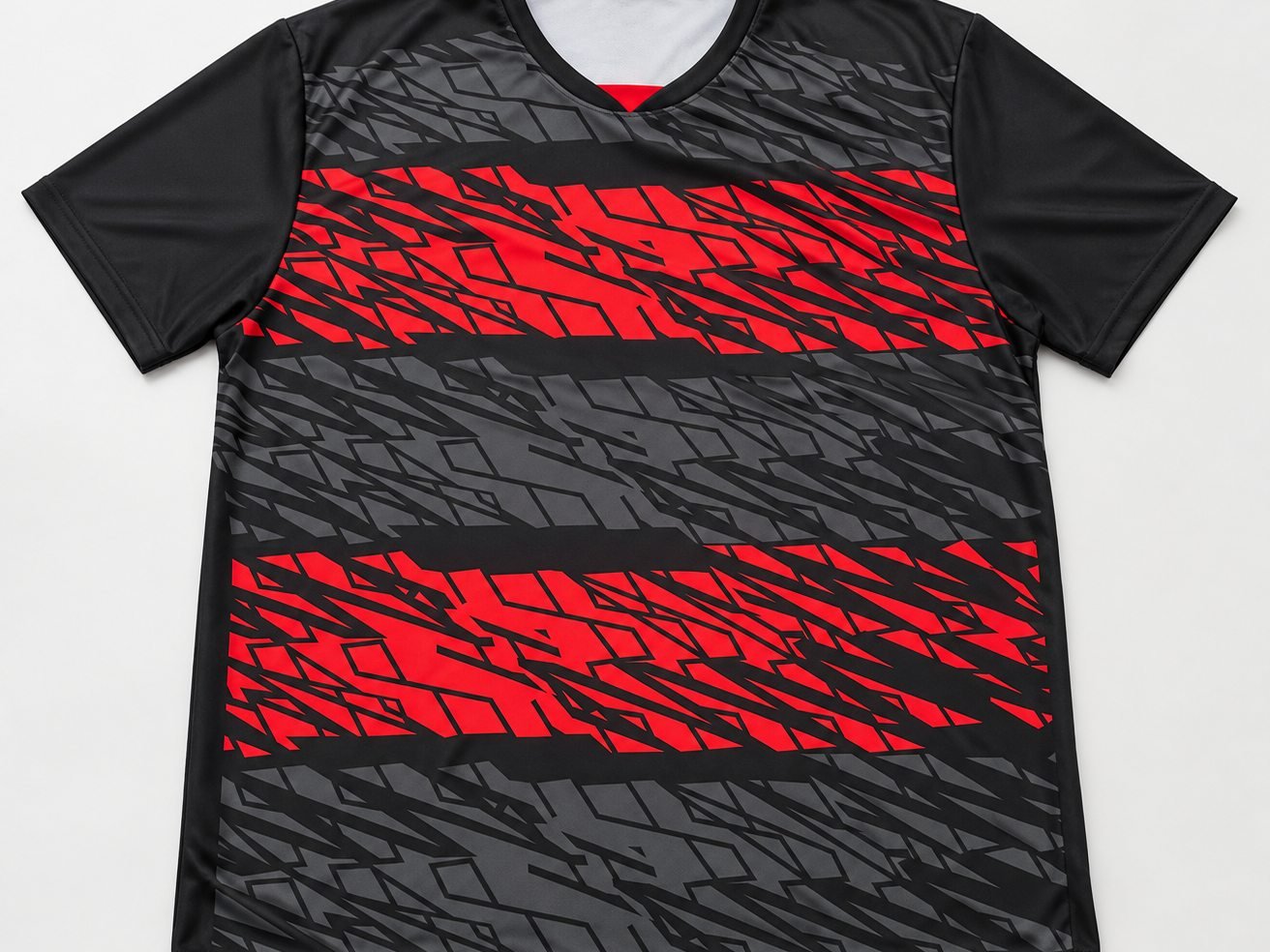 Camisa esportiva em sublimação: faixas geométricas em vermelho e cinza sobre fundo preto, estampa que cobre a peça inteira